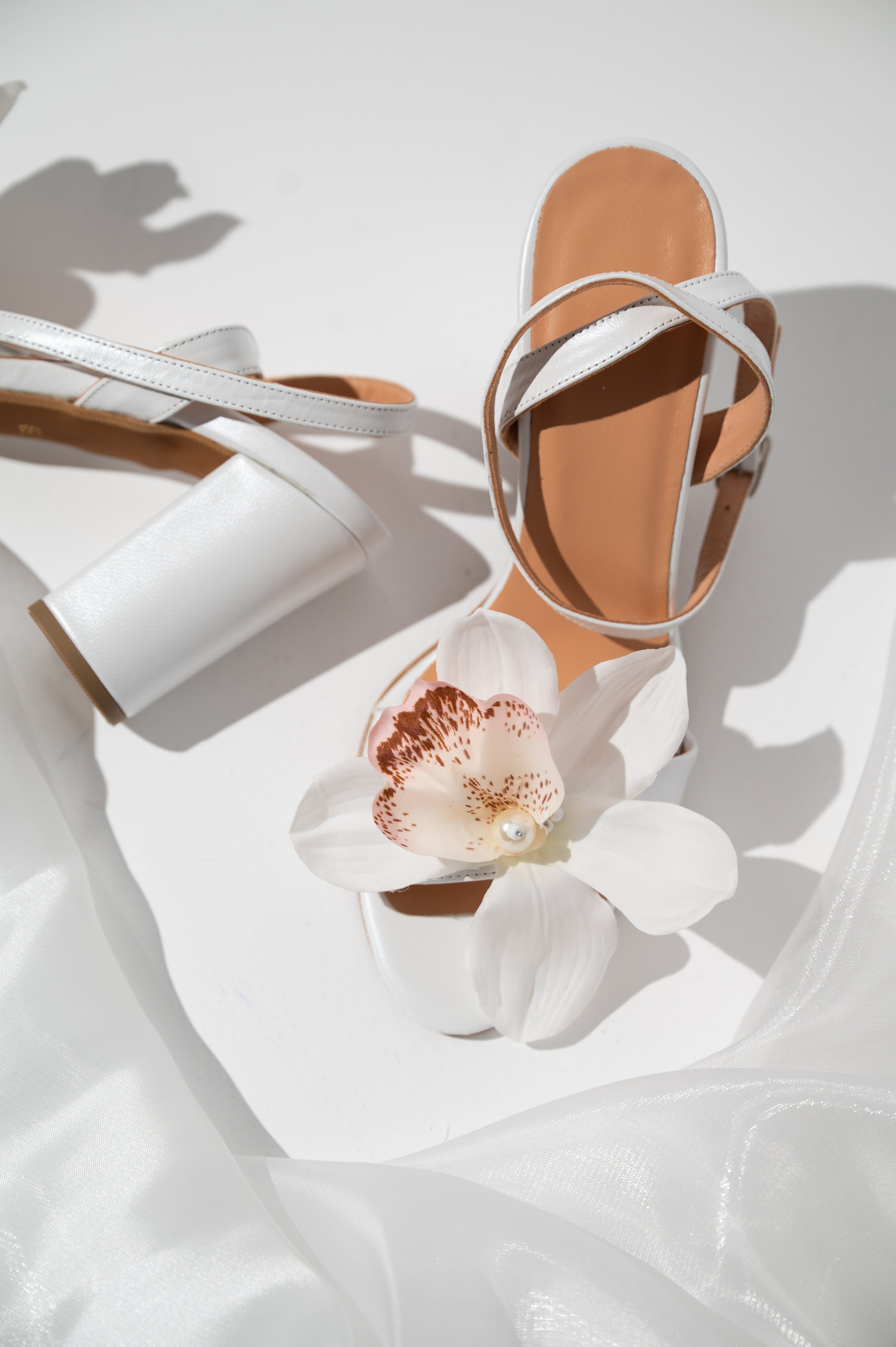 White sandal with a decorative flower on a white background